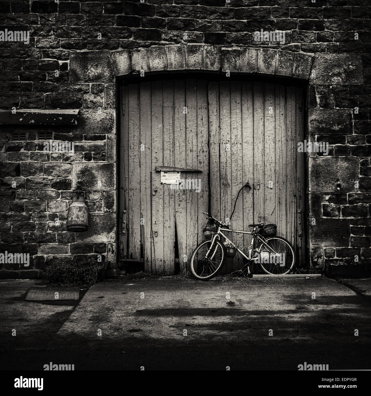 Un vecchio fienile porta a una fattoria di latte con un bidone di ghiaccio dicendo di latte freddo Foto Stock