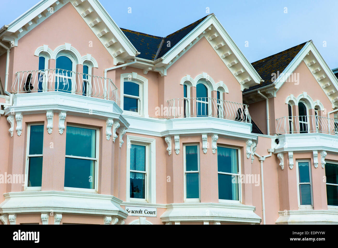 Rosa pastello tradizionale dipinto appartamenti sul mare a Seacroft corte lungo la costa inglese a Teignmouth nel South Devon, Regno Unito Foto Stock