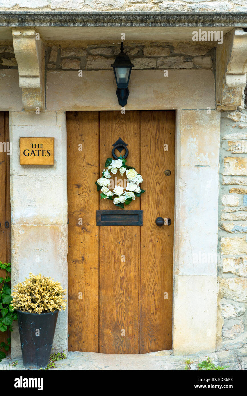 Inglese tradizionale legname di quercia sportello anteriore del cottage del paese con una ghirlanda di fiori nel pittoresco villaggio di Castle Combe in Cotswo Foto Stock