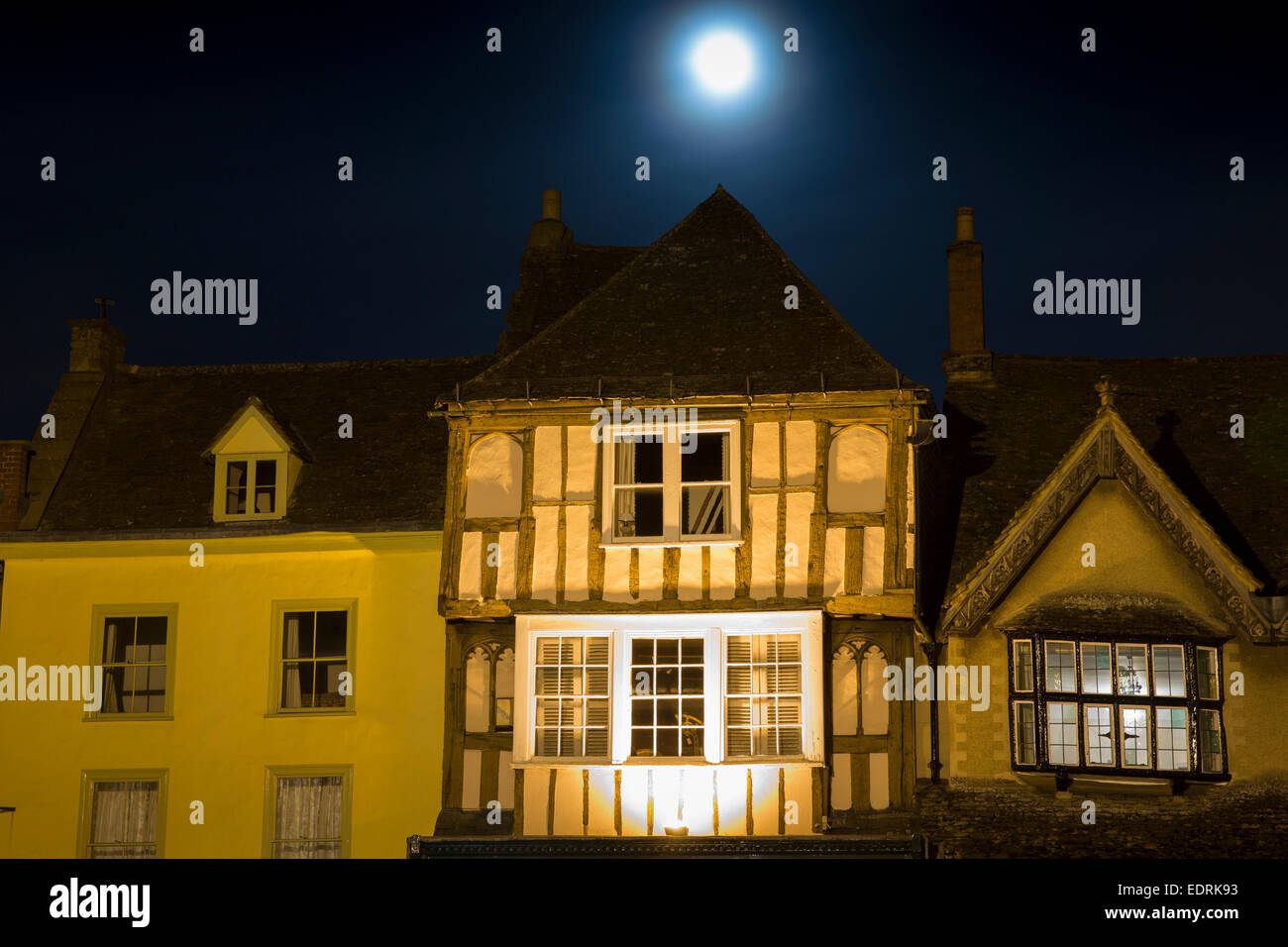 Luna piena che brilla sulla antica architettura medievale lungo Burford High Street di notte, i Cotswolds Foto Stock
