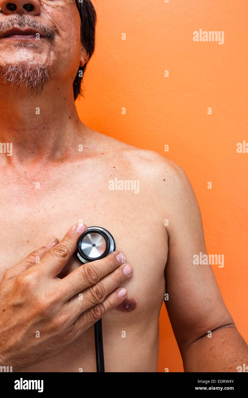 Vecchia età uomo asiatico è stato diagnosticato dal medico su sfondo arancione Foto Stock