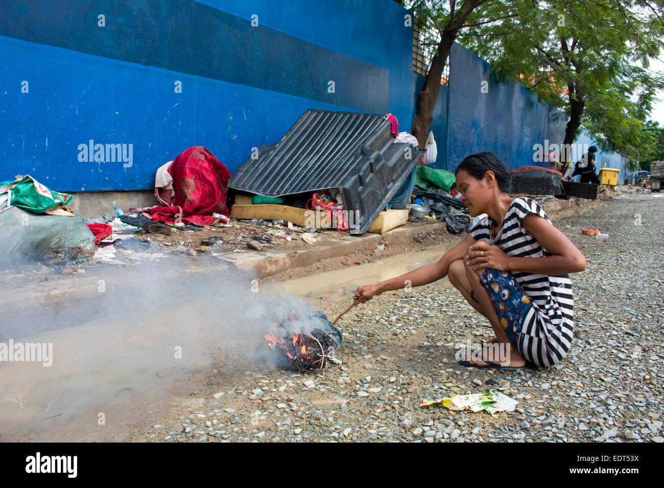 Una donna che lavora come scavenger brucia immondizia davanti al suo rifugio adiacente al Parco Freedom in Phnom Penh Cambogia. Foto Stock