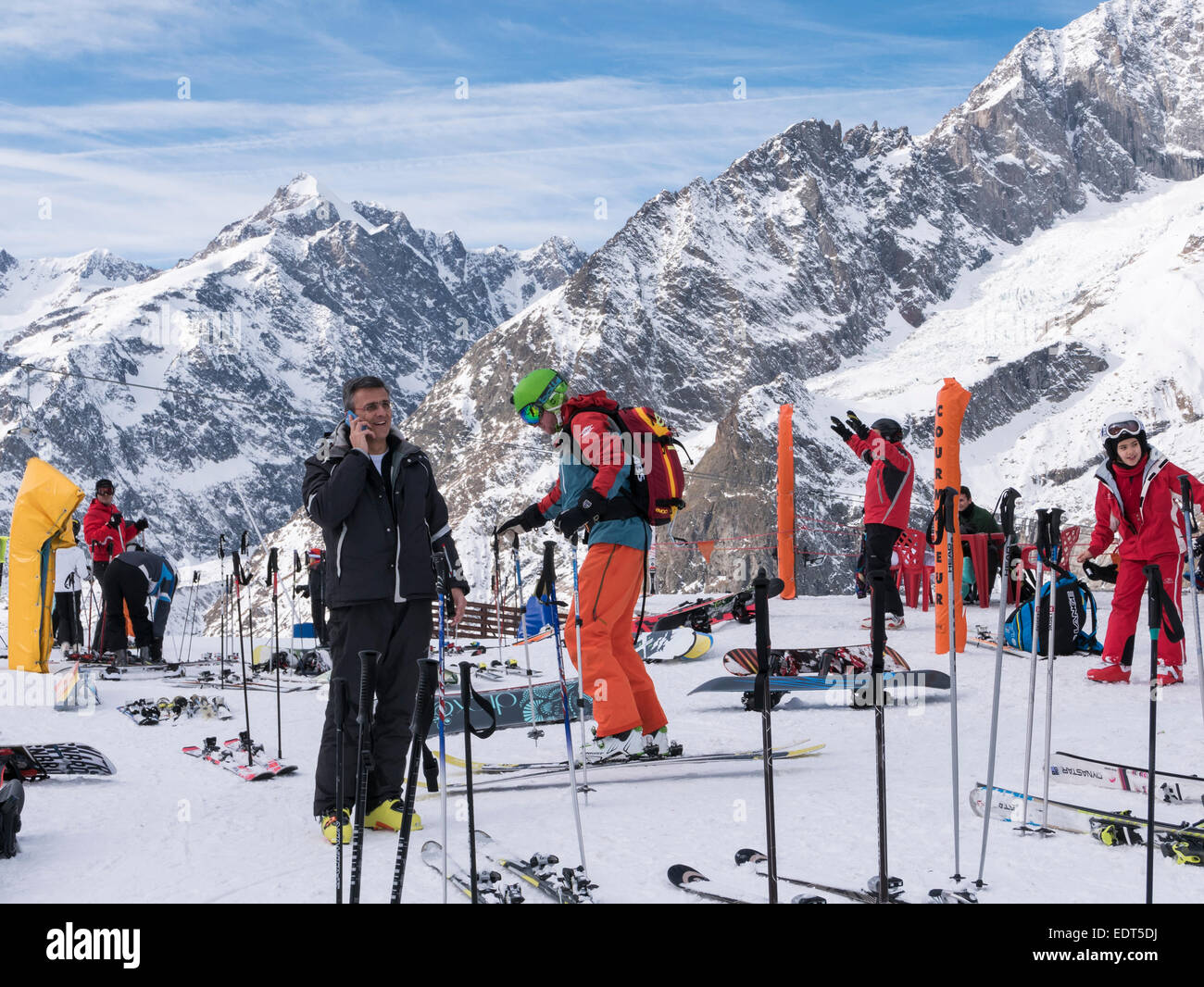 Gli sci e gli sciatori sulle piste innevate con il massiccio del Monte Bianco nelle Alpi Graian dietro. Courmayeur, Valle d'Aosta, Italia, Europa Foto Stock