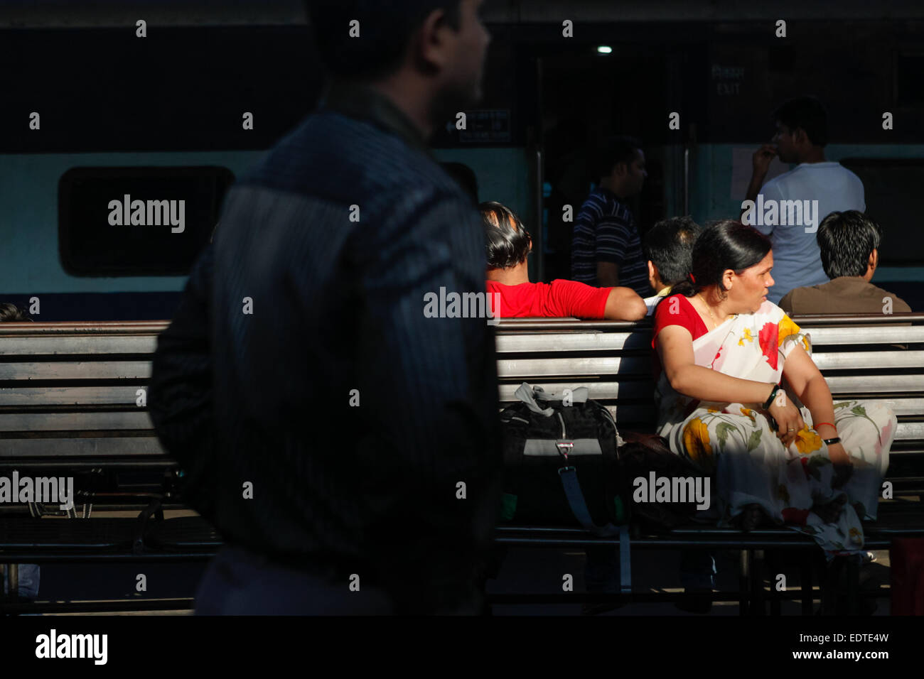 Una donna passeggero è in attesa per l'orario di partenza come lei è seduta su una panchina sulla piattaforma passeggeri a Nuova Delhi Stazione ferroviaria a Delhi, India. Foto Stock