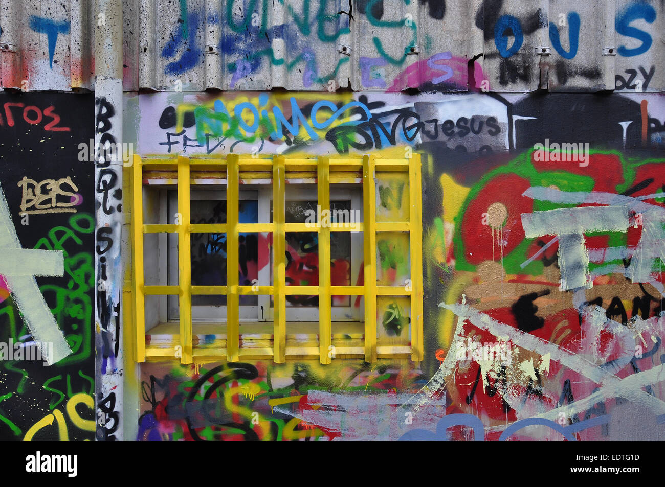 Finestra sbarrata e parete ricoperta con graffiti disordinato e macchie di vernice. Foto Stock