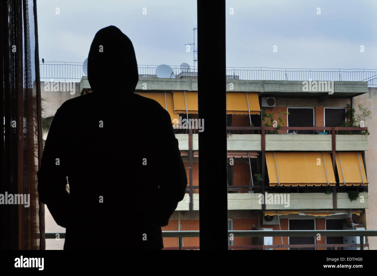 Uomo che guarda gli edifici della città attraverso la finestra. Foto Stock
