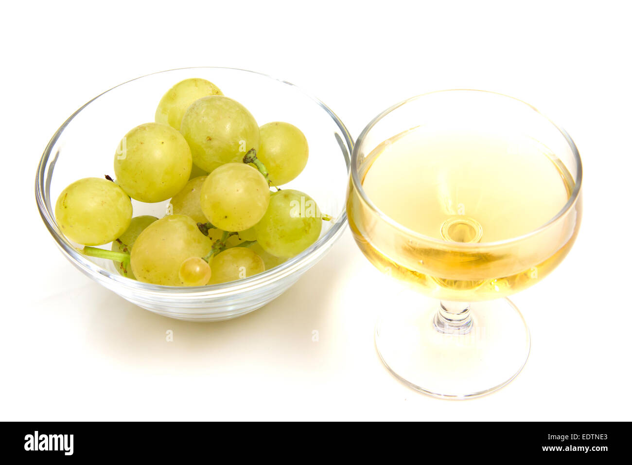 Un bicchiere di vino e di uve in una ciotola su sfondo bianco Foto Stock