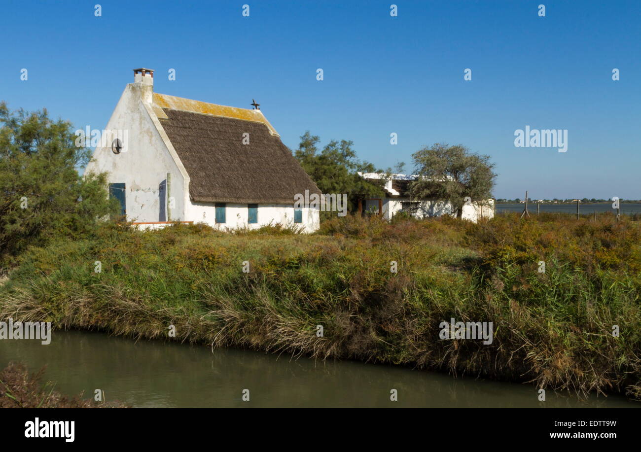 Tipica casa custode accanto a un piccolo canale per acqua dal bel tempo, Camargue, Francia Foto Stock