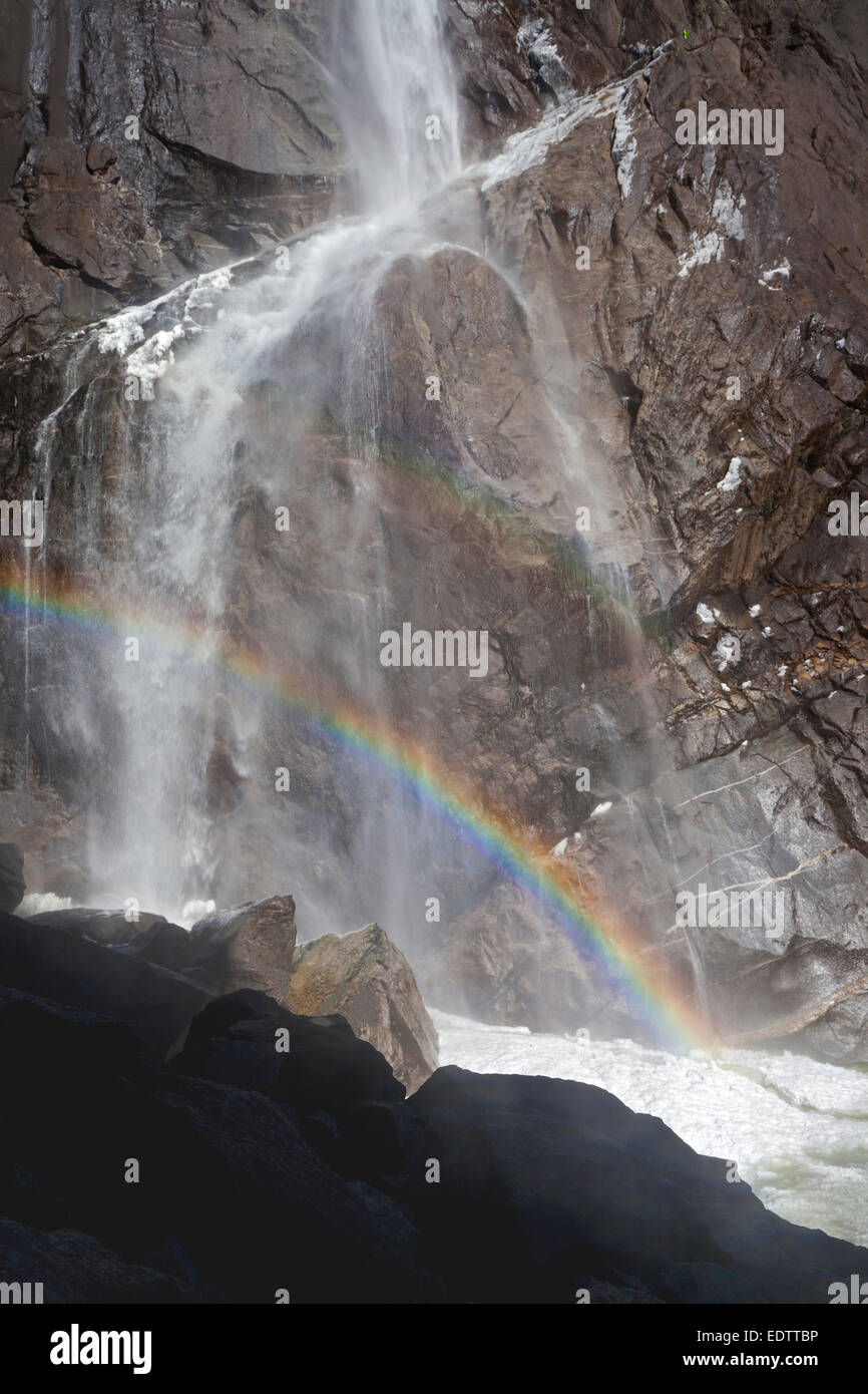 Acqua, arcobaleno e frazil ghiaccio in corrispondenza della base inferiore di Yosemite Falls nel Parco Nazionale di Yosemite Foto Stock