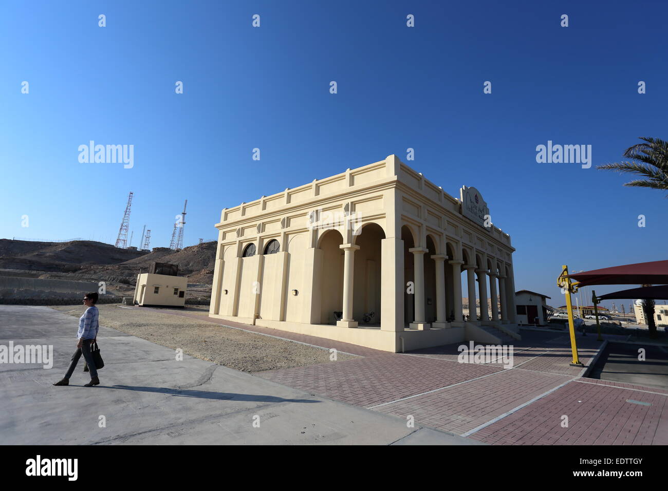 Donna oltrepassando il Bahrain il Museo dell'olio, con Jebel Al-Dukhan in background, Regno del Bahrein Foto Stock