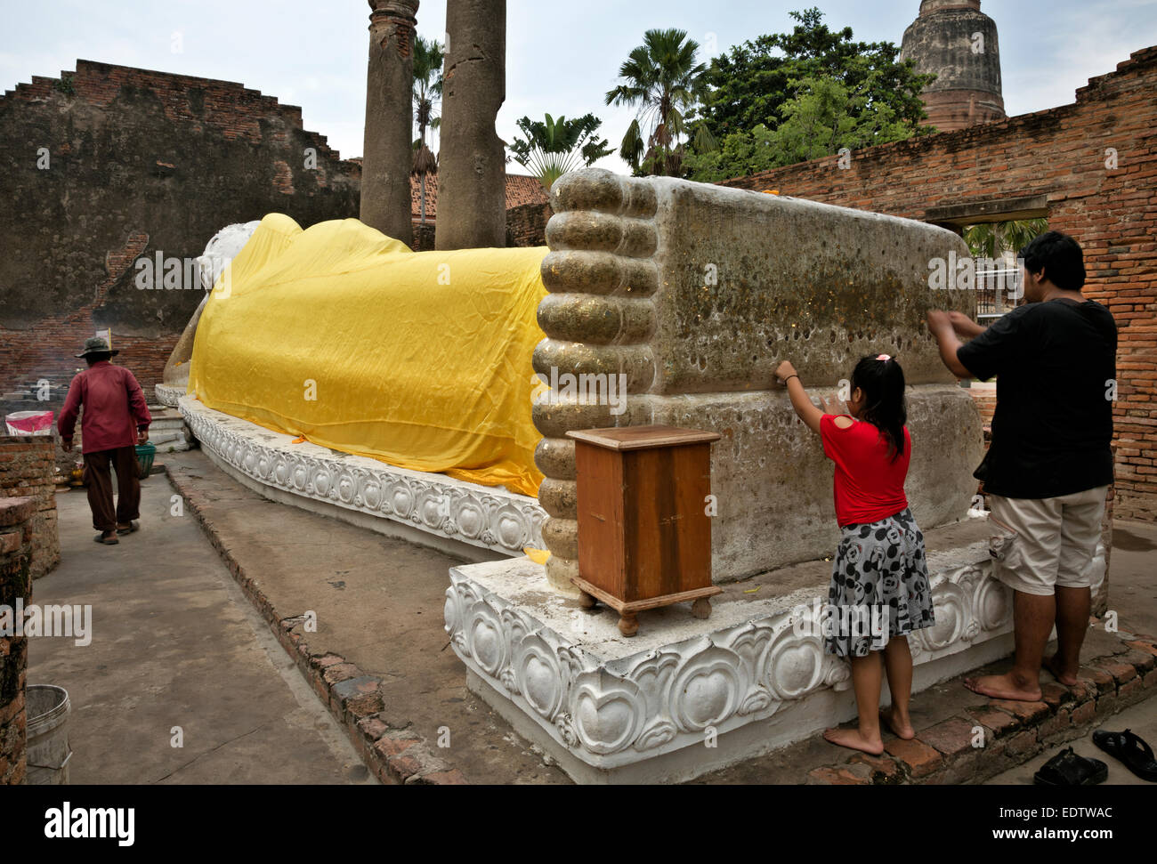 Thailandia - visitatori il merito di guadagno premendo poco macchie di foglia oro su Buddha reclinato al Wat Chai Mongkol in Ayutthaya Foto Stock