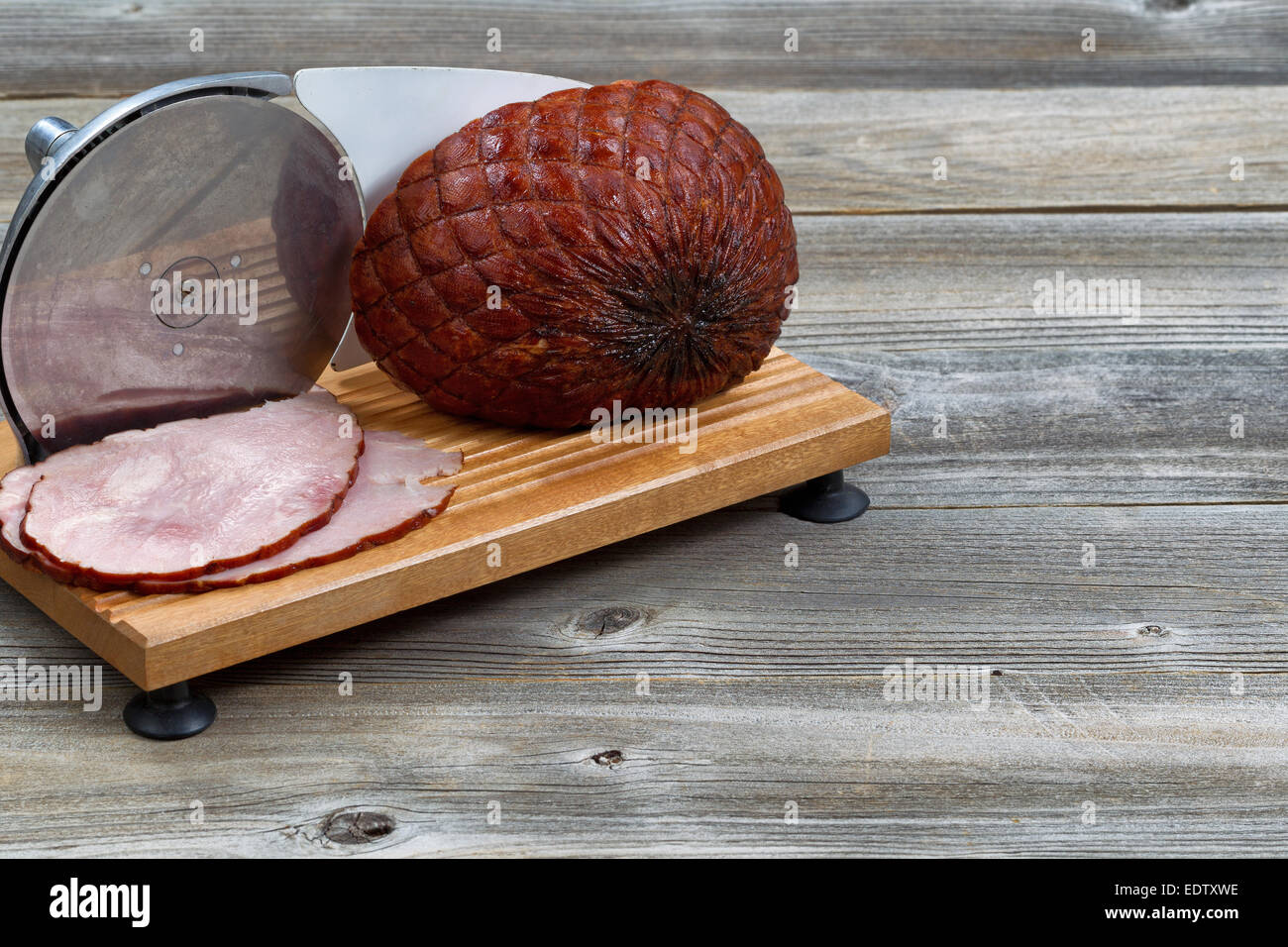L'immagine orizzontale di prosciutto affumicato e carni macchina affettatrice su legno rustico Foto Stock
