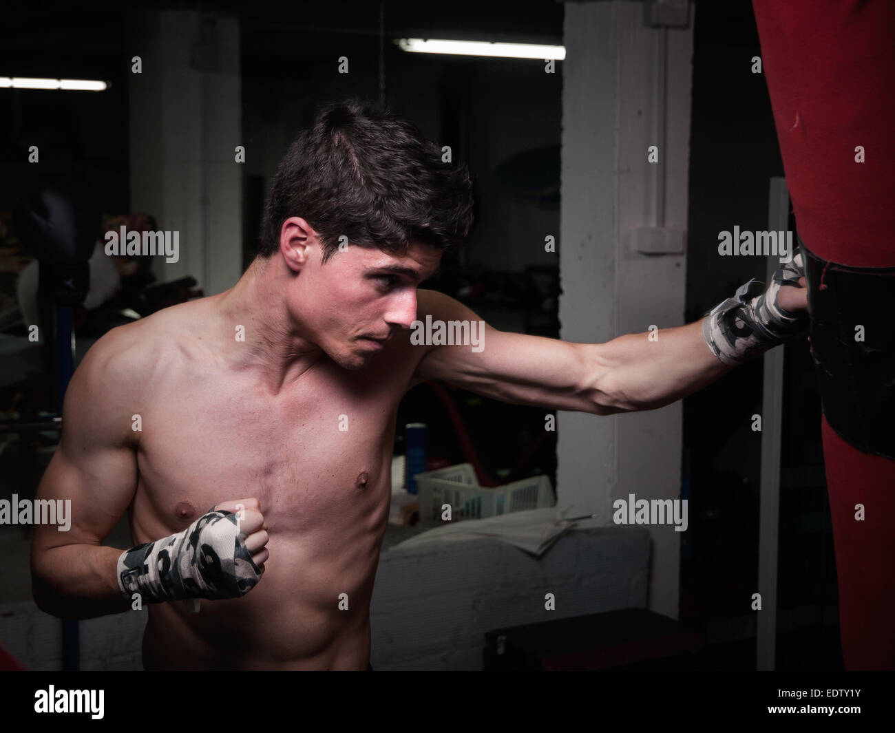 Giovani caucasici formazione Boxer con un sacco da boxe in casa sua palestra Foto Stock