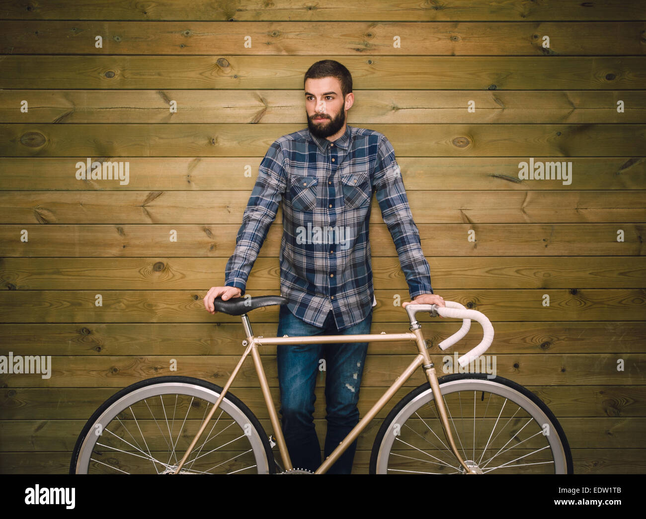 Hipster uomo con la sua fixie bike su uno sfondo di legno Foto Stock