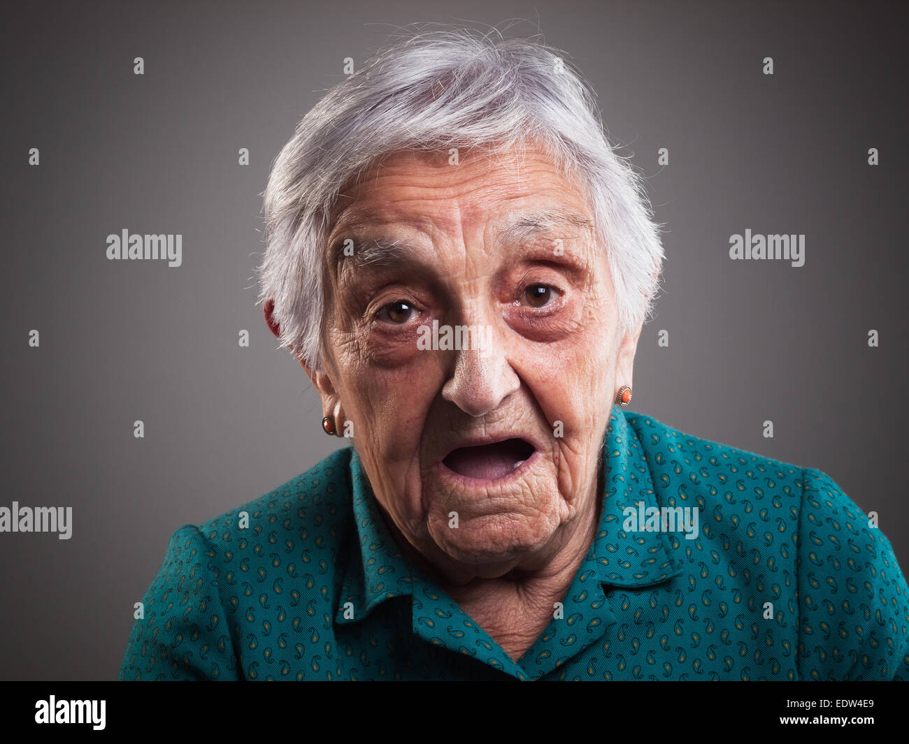 Donna anziana con espressioni di sorpresa e isolato su sfondo scuro Foto Stock