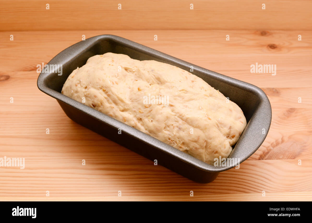 Materie avena e semi di lino di pasta di pane in un 2lb focaccia stagno su una tavola di legno Foto Stock