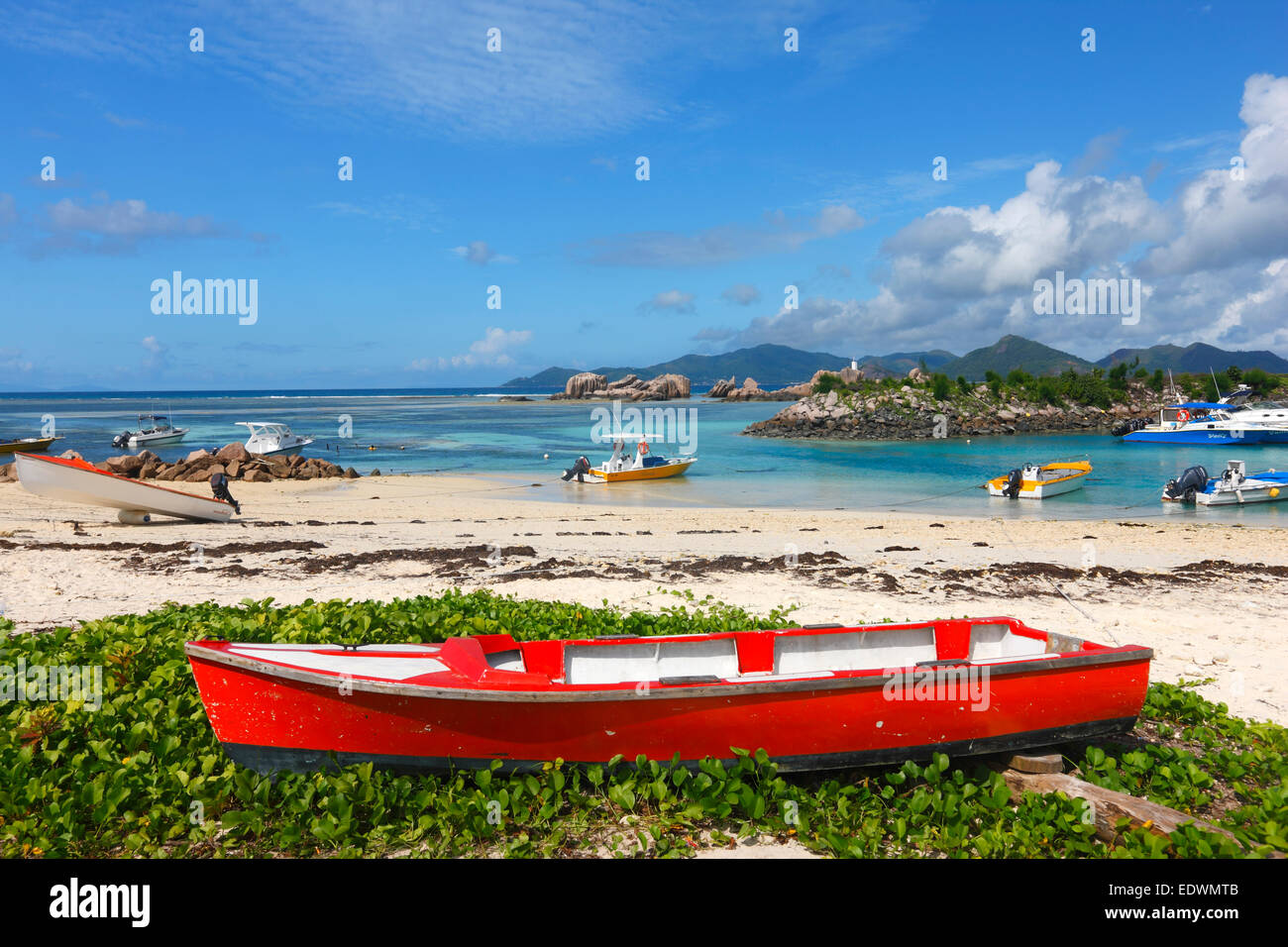 Rosso barca sulla spiaggia di sabbia. Isola di La Digue e le Seicelle. Foto Stock