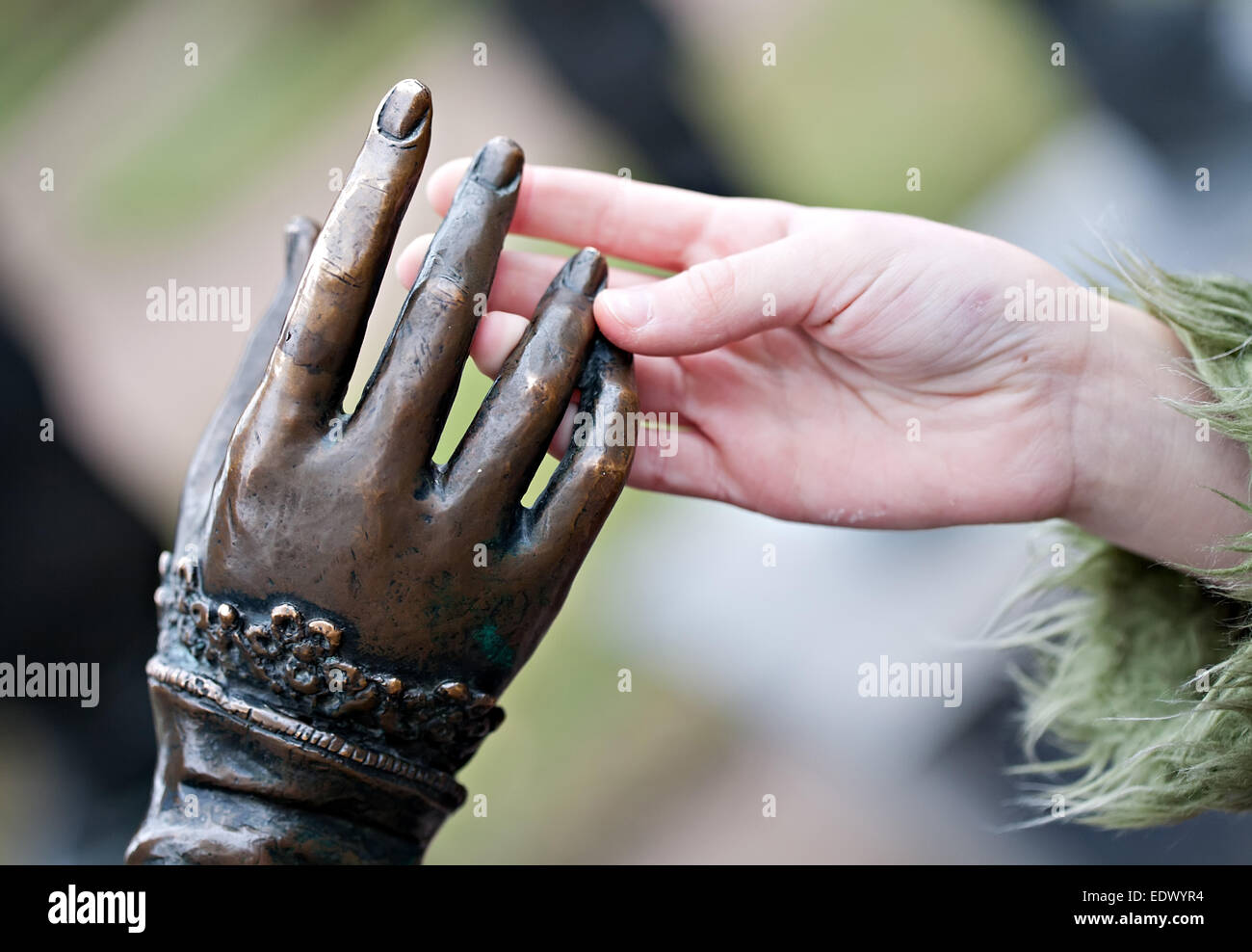 Toccare closeup di due mani: Statua di metallo e bambino umano Foto Stock