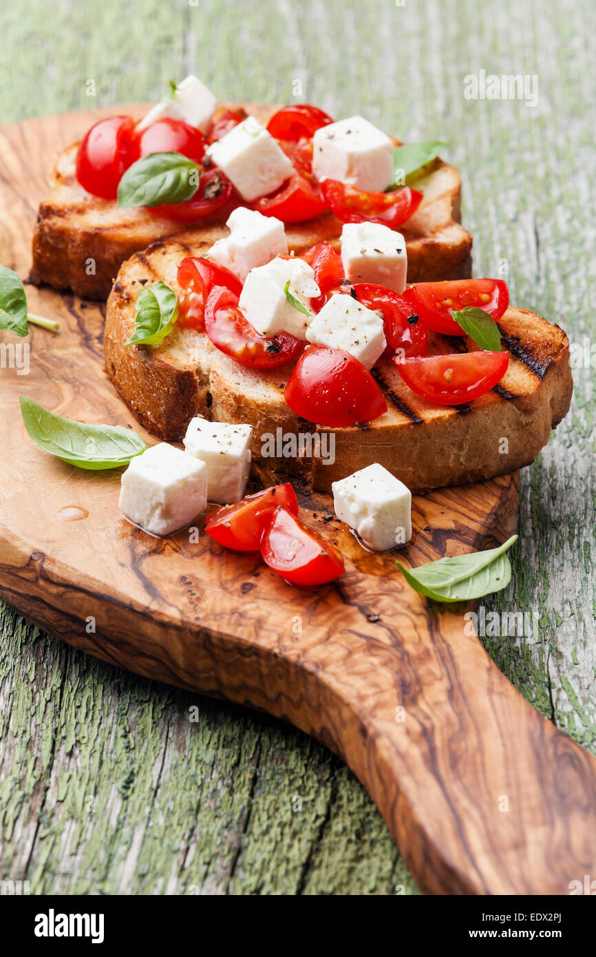 Bruschetta con pomodori tritati, il basilico e il formaggio su grigliate di crosta di pane Foto Stock