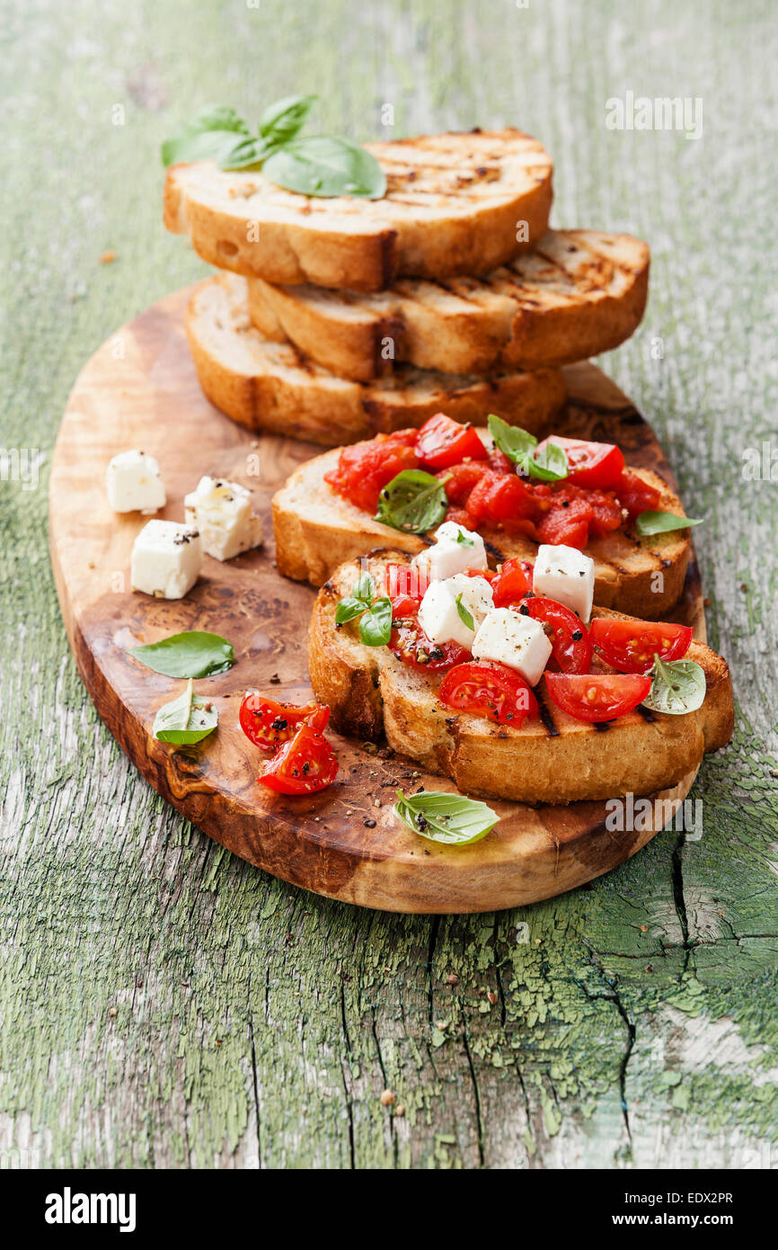 Bruschetta con pomodori tritati, il basilico e il formaggio su grigliate di crosta di pane Foto Stock