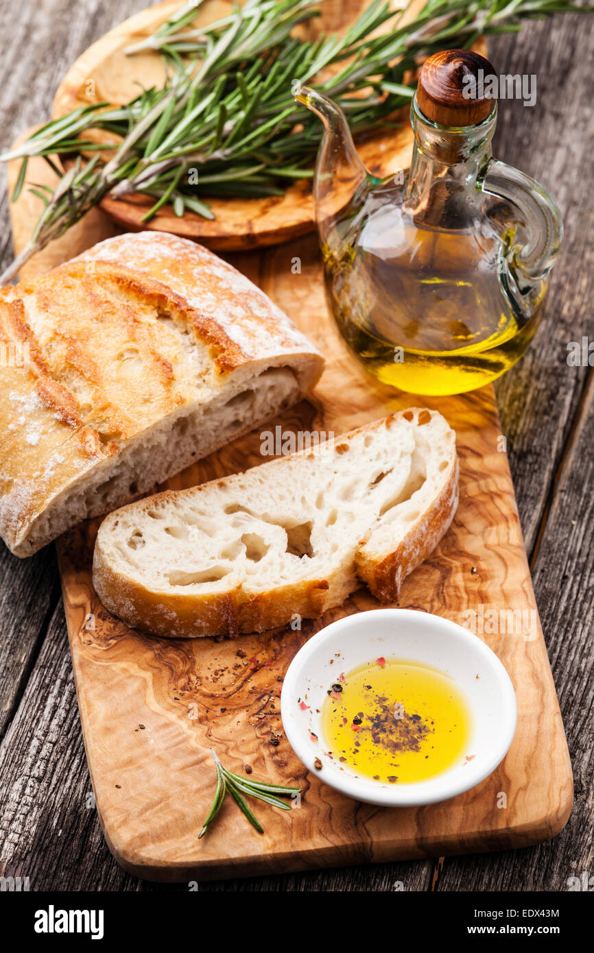 Fette di pane Ciabatta e olio extra vergine di oliva su legno d'ulivo pentole sfondo Foto Stock