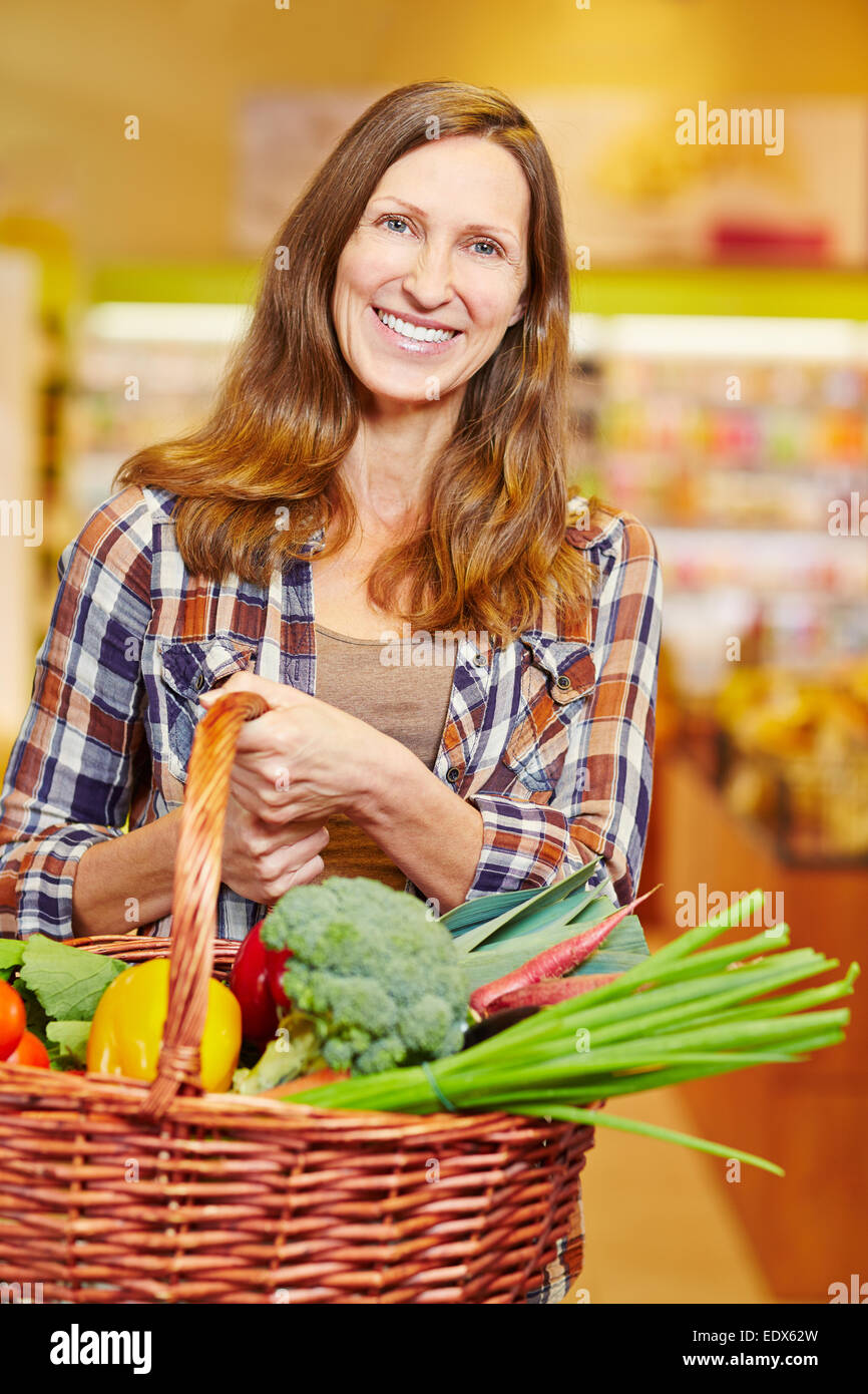 Attraente donna anziana che trasportano carrello pieno di verdure fresche Foto Stock