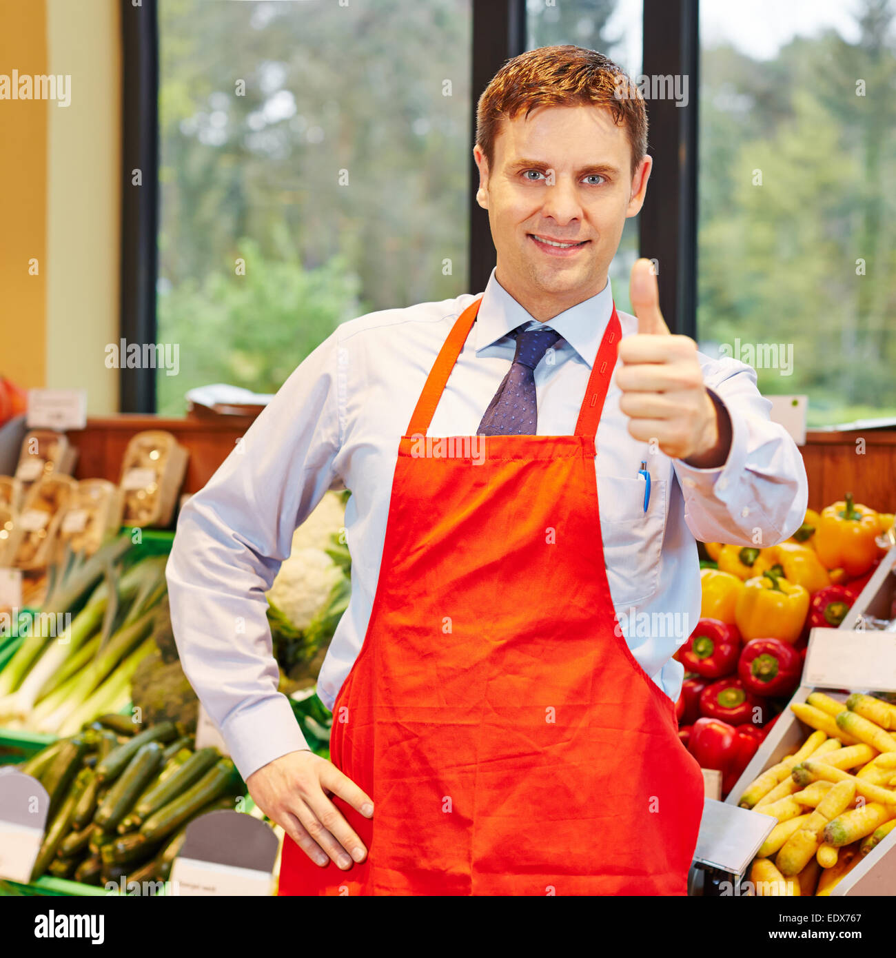 Sorridendo felice supermercato dipendente tenendo il suo pollice in alto Foto Stock
