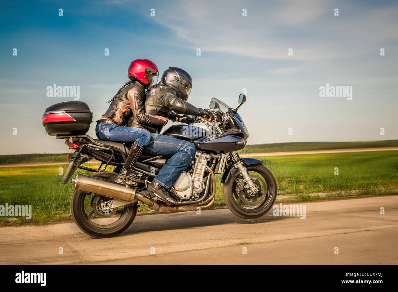 Giovane biker in una giacca di pelle in sella a una motocicletta sulla strada Foto Stock
