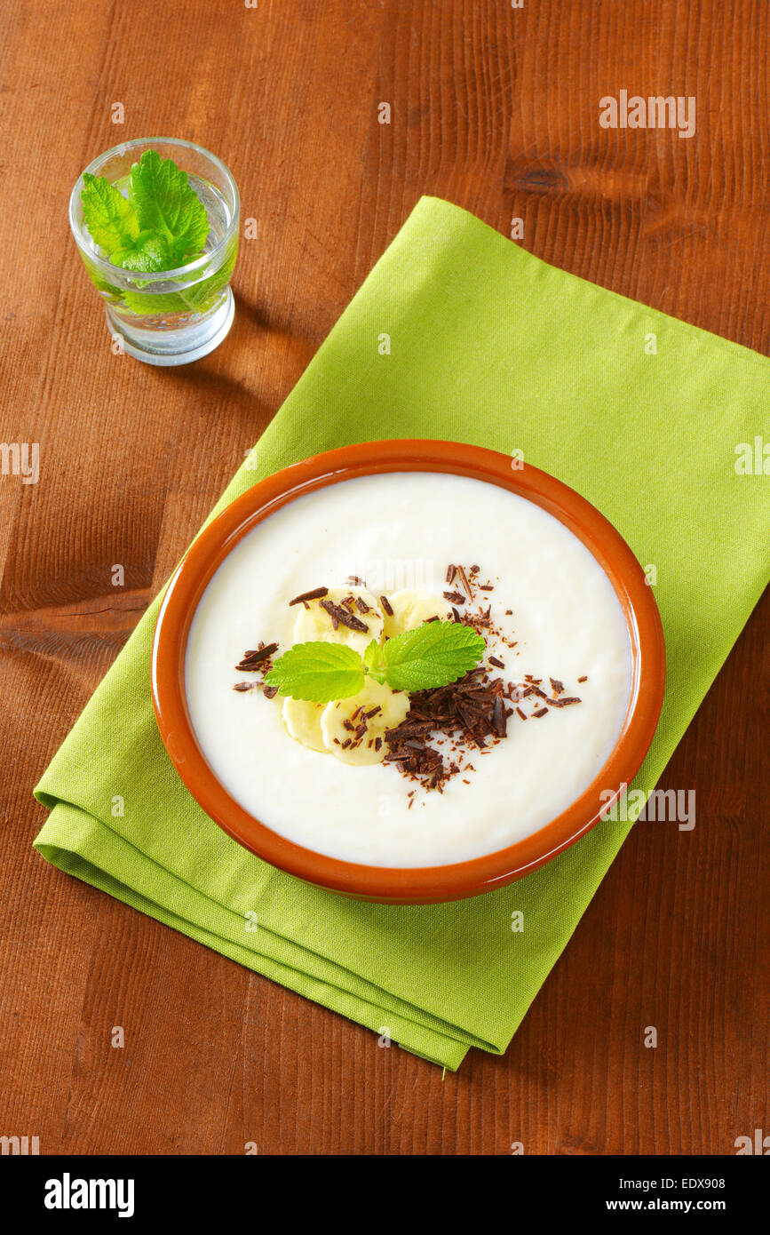 Ciotola di liscio budino di latte con fette di banana e cioccolato grattugiato Foto Stock