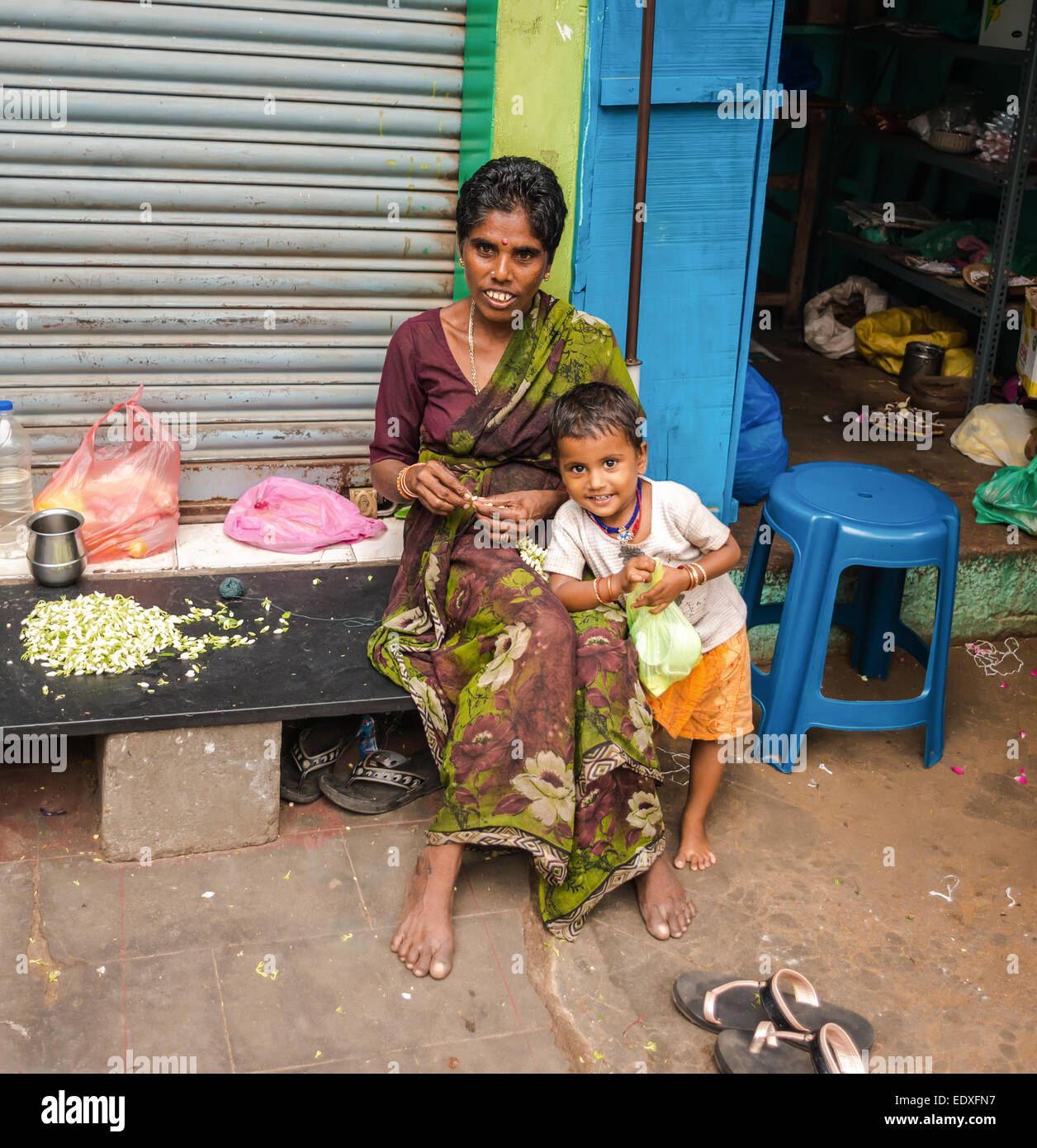 THANJAVOUR, India - 14 febbraio: una donna non identificato con il bambino nel tradizionale abbigliamento indiano sono seduti. La donna tesse una garla Foto Stock