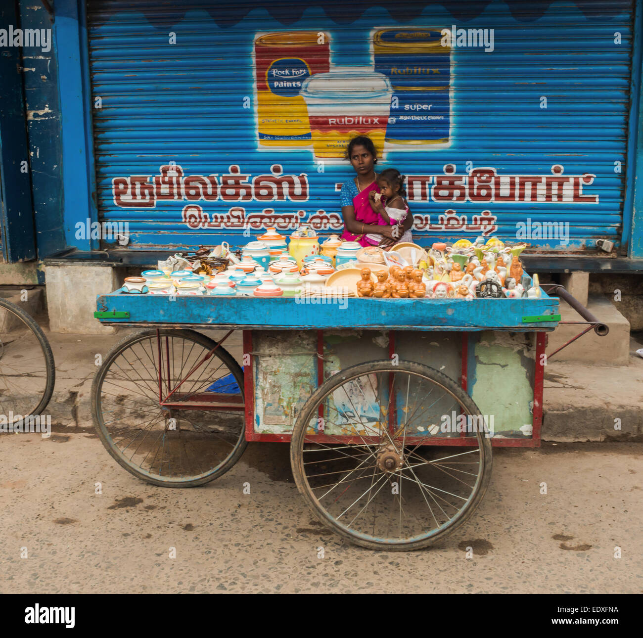 THANJAVOUR, India - 14 febbraio: una donna non identificato tenendo un bambino e seduto dietro il bancone con negozio di souvenir. India, Tami Foto Stock