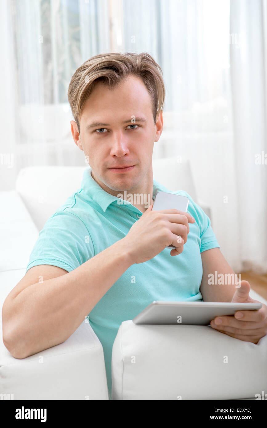 Uomo con gadget seduti a casa Foto Stock