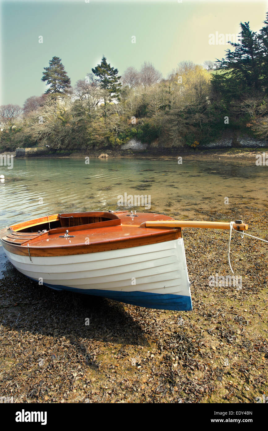 Una piccola barca a vela ancorata al di sopra della linea di acqua su una spiaggia di roccia argillosa sull'estuario del fiume Dart nel Devon. Foto Stock