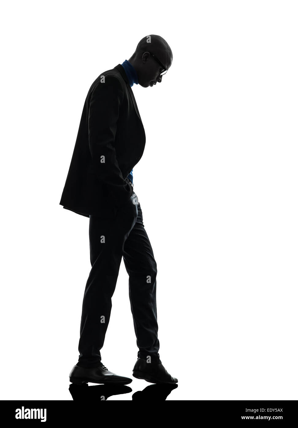 Uno nero africano man standing guardando giù in silhouette studio su sfondo bianco Foto Stock