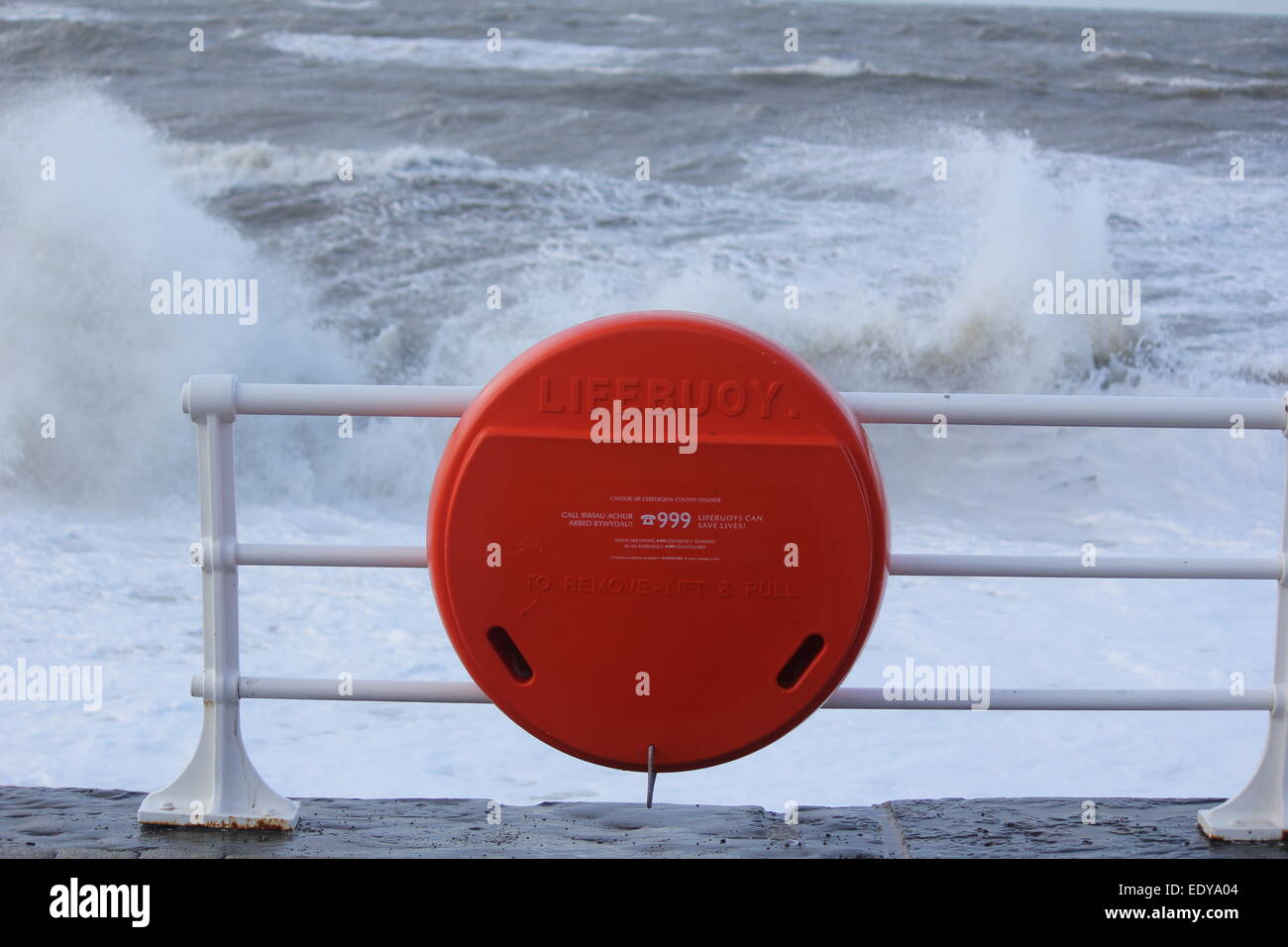 Aberystwyth West Wales UK..un salvagente situato sul lungomare con gale force winds & arrabbiato mari battendo la linea costiera. Foto Stock