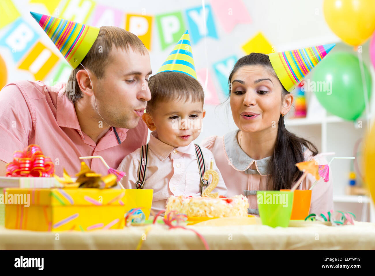Bambino con i genitori colpo candela sulla torta di compleanno Foto Stock