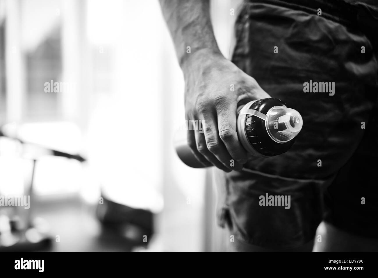 La mano del giovane azienda bottiglia con acqua in palestra Foto Stock