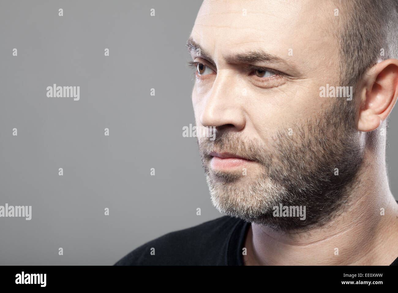 Uomo che guarda a sinistra isolata su uno sfondo grigio con copyspace Foto Stock