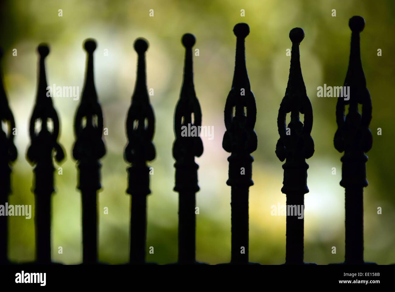 Cimitero di ferro battuto recinzione rende le strane forme contro lo sfondo grigio come sentinelle del cimitero di guardia Foto Stock