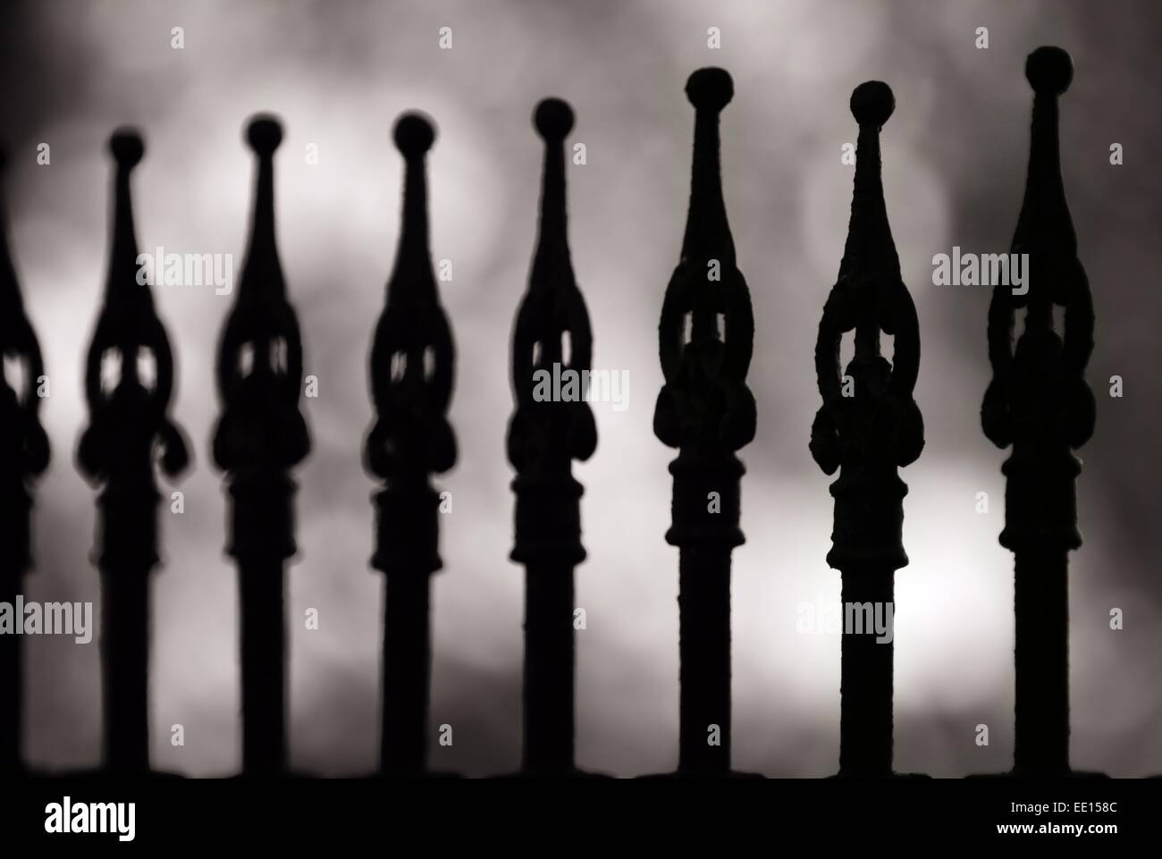 Cimitero di ferro battuto recinzione in bianco e nero rende le strane forme contro uno sfondo grigio Foto Stock