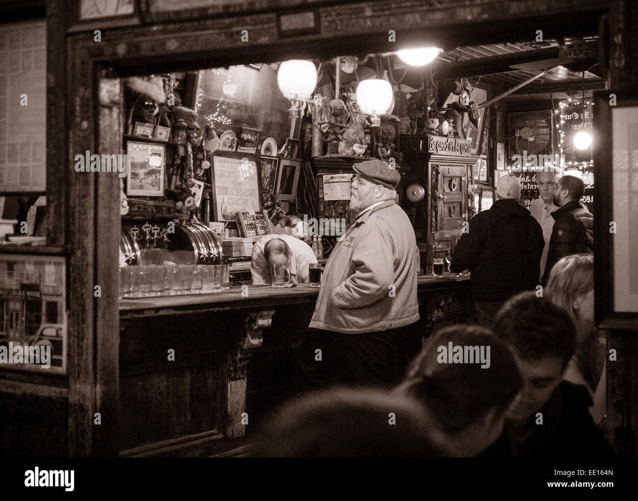 Il bar a McSorley's Old Ale House: monocromatico. Un uomo si erge al bar mentre il bar gara recupera qualcosa al di sotto della barra Foto Stock
