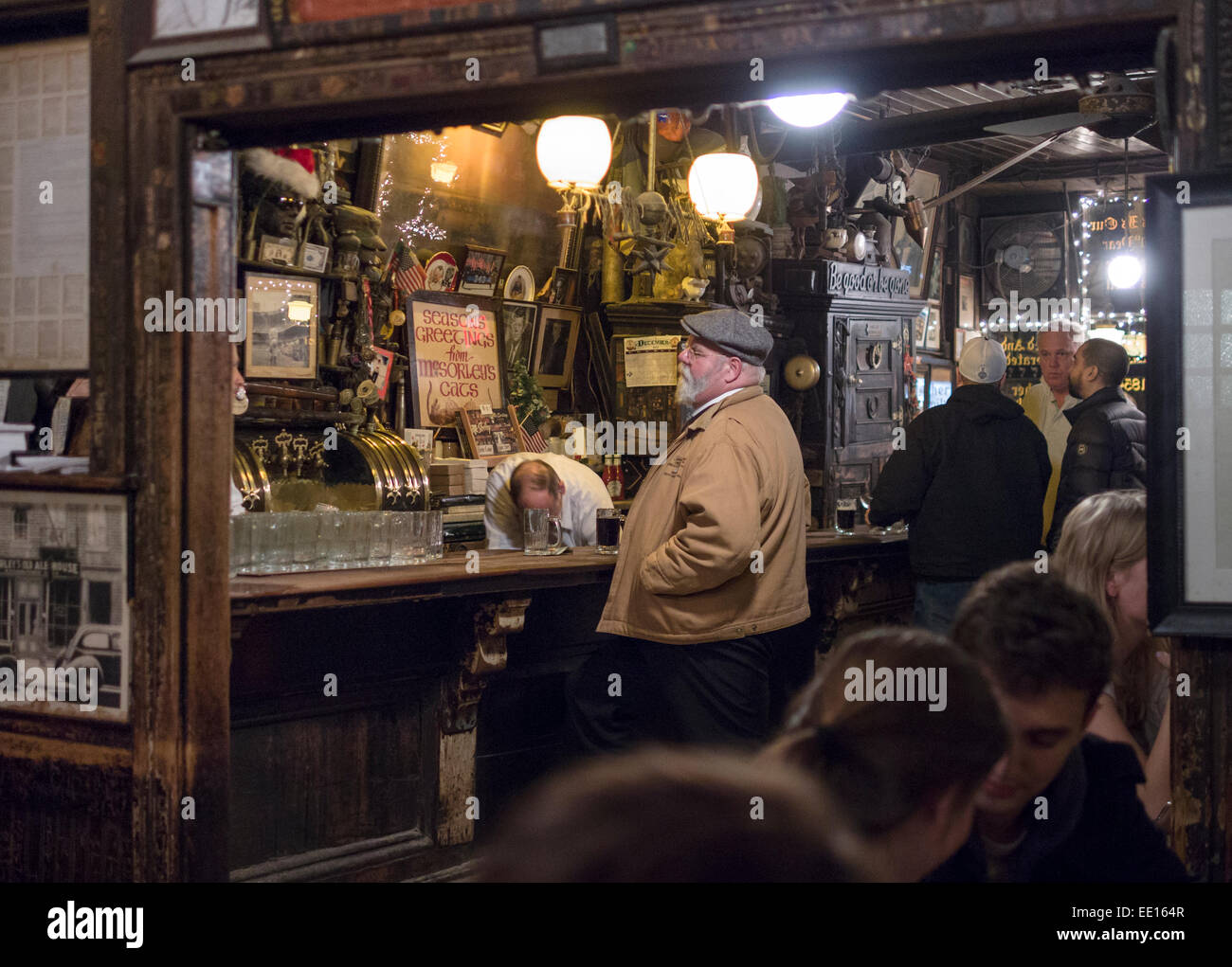 Il bar a McSorley's Old Ale House. Un uomo si erge al bar mentre il bar gara recupera qualcosa sotto il contatore Foto Stock