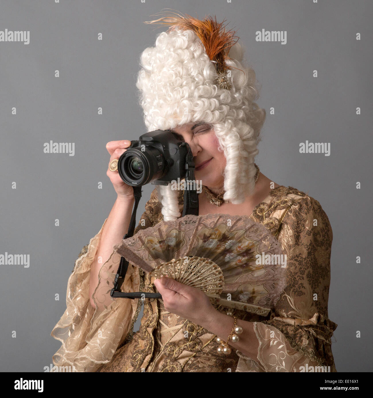 Donna vestita di un costume del periodo rococò e trattenimento di un ventilatore di pizzo fotografare con fotocamera moderna Foto Stock