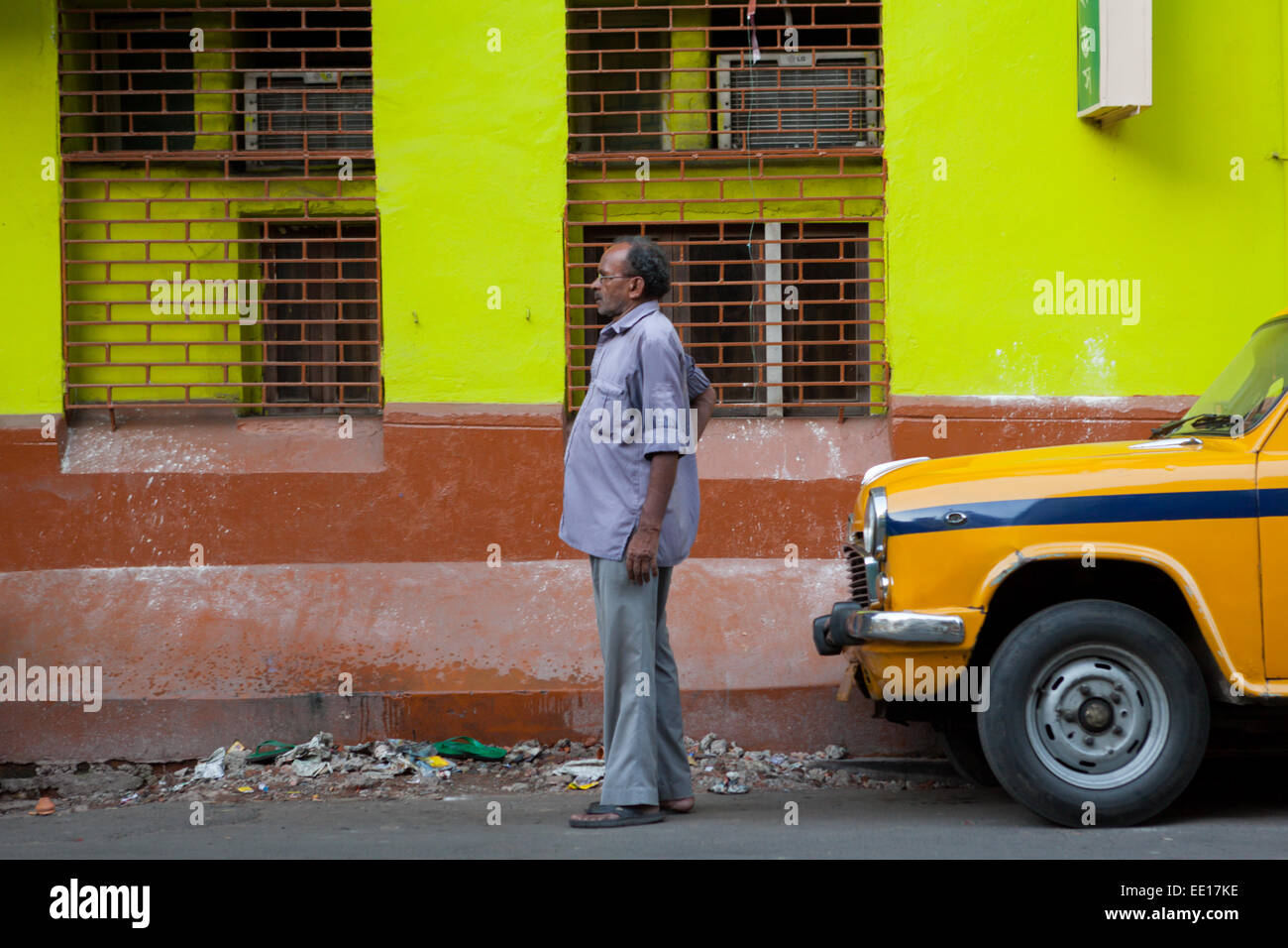 Tassista in attesa di passeggeri, in piedi su una strada stretta vicino a Sudder Street a Kolkata, India. Foto Stock