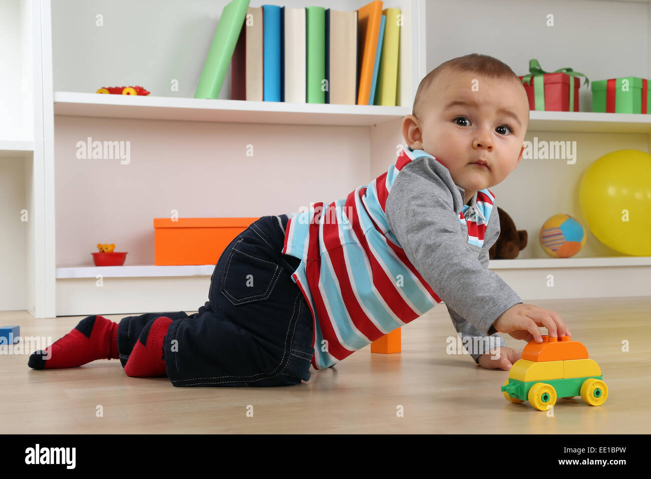Ritratto di un simpatico baby giocando con auto giocattolo in camera per bambini Foto Stock