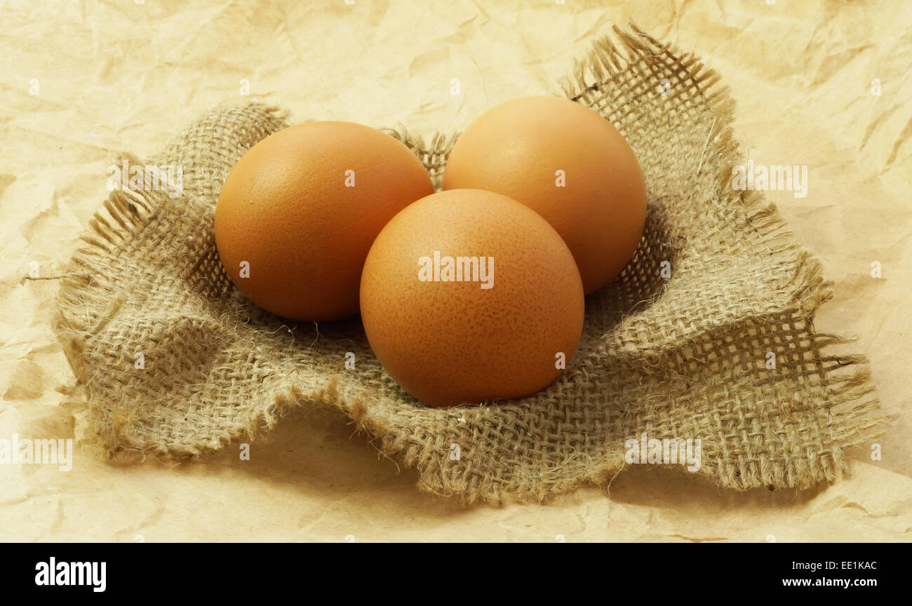 Le uova organiche sul sacco e carta marrone dello sfondo. Messa a fuoco selettiva Foto Stock