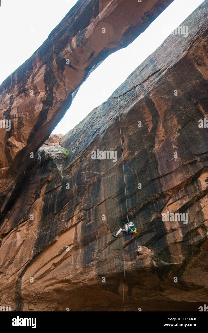 Donna rapelling giù un arco gigante, canyoning, Moab, Utah, Stati Uniti d'America, America del Nord Foto Stock