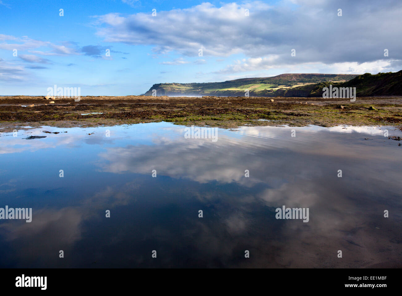 Il Cloud riflessioni in una piscina di marea a Robin cappe Bay, Yorkshire, Inghilterra, Regno Unito, Europa Foto Stock