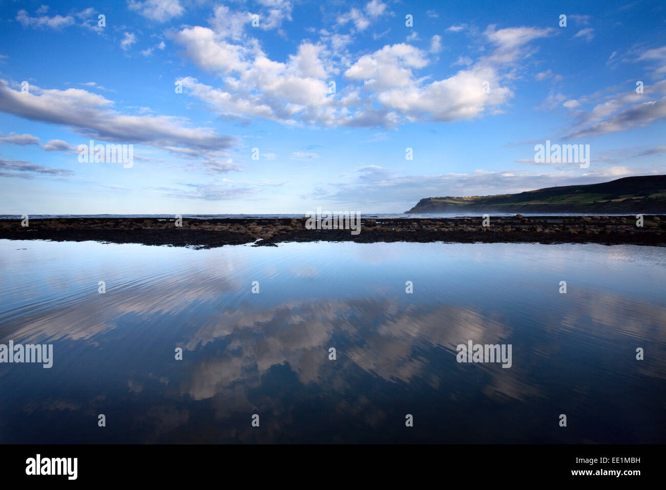 Il Cloud riflessioni in una piscina di marea a Robin cappe Bay, Yorkshire, Inghilterra, Regno Unito, Europa Foto Stock