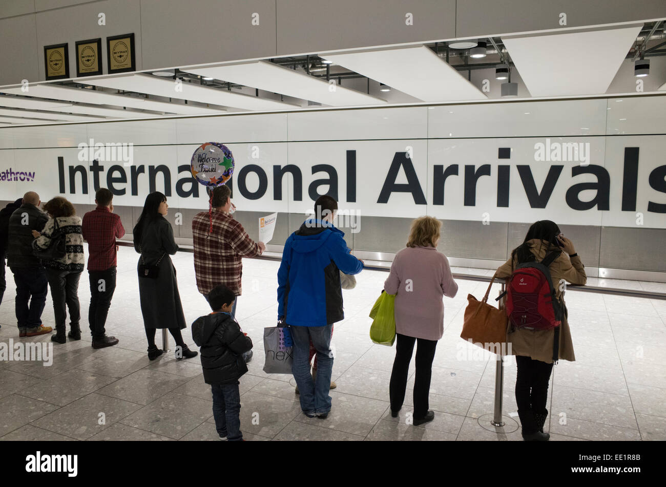 La gente in attesa presso gli Arrivi Internazionali dell'aeroporto di Heathrow in Gran Bretagna Foto Stock